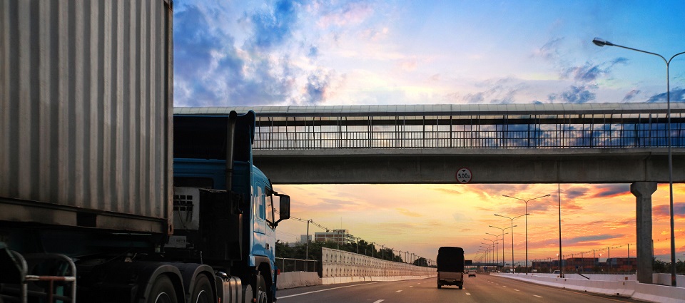 Two trucks on highway with sunrise in background